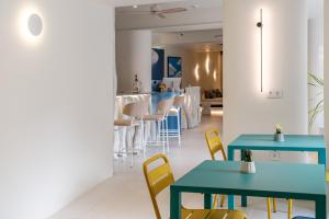 a restaurant with blue tables and yellow chairs at Noera in Skiathos +19 photos