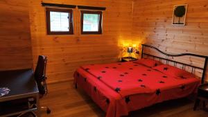 a bedroom with a red bed in a wooden room at SkyhighRetezat in Clopotiva