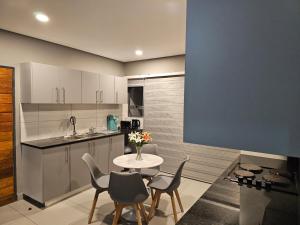 a kitchen with a table and some chairs and a table and a counter at Sky Apartment Mbabane CBD in Mbabane