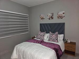 a bedroom with a bed with purple sheets and a window at Sky Apartment Mbabane CBD in Mbabane