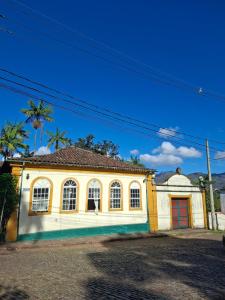 a yellow and white house with a red door at Pouso das Glicínias - B&B in Ouro Preto