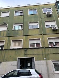 a green building with a car parked in front of it at Rooms Moscavide quartos in Lisbon