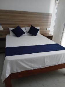 a large bed with blue and white sheets and pillows at Kimbar Suites in Mombasa