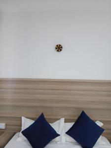 a bed with blue pillows and a clock on the wall at Kimbar Suites in Mombasa