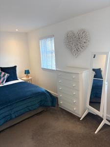 a bedroom with a bed and a dresser and a mirror at 1 Shiphouse Apartment in Lamlash