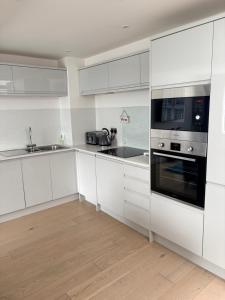 a white kitchen with white cabinets and a microwave at 1 Shiphouse Apartment in Lamlash