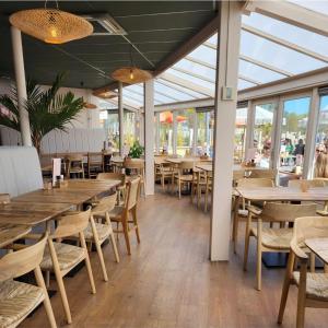 a restaurant with wooden tables and chairs and windows at Tiny House in Kropswolde