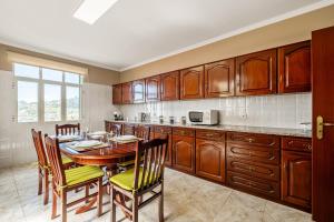 a kitchen with wooden cabinets and a table and chairs at Villa Vineyard by Homie in Câmara de Lobos