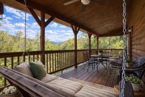 a porch with a swinging couch and a table on a deck at Wilderness Lodge, Hot Tub, Pool Table, Pool Access, WIFIeach paid day in Sevierville