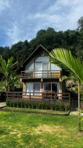 a house with a palm tree in front of it at cabana refúgio in Paulo Lopes