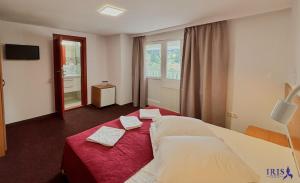 a hotel room with a bed with two towels on it at Pensiunea Iris in Băile Tuşnad