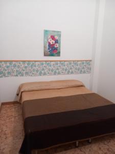a bed in a bedroom with a painting on the wall at Habitaciones turísticas copitos in Gandía