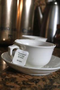 a white cup on a plate with a tag on it at Casa Ligia in Medellín