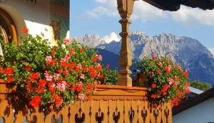 a window with flowers on a balcony with mountains at Ferienwohnung KARWENDEL in Krün +10 photos