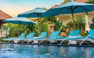 a group of chairs and umbrellas next to a pool at Bali Nusa Cottage in Nusa Lembongan