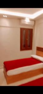 a bedroom with a large red bed with two windows at ريم الفلا in Dawwār Abū Maḩrūs