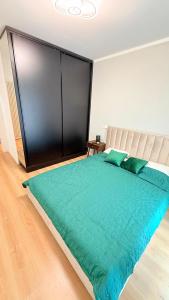 a bedroom with a large bed with a green comforter at TRIO Sun Class Park Residence in Târgovişte +4 photos