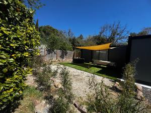 a house with a yellow curtain in a yard at Bungalow jacuzzi & jardin privatif séjour détente au soleil in La Crau