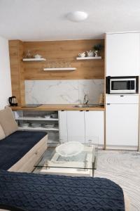 a kitchen with white cabinets and a glass table at Ćato s cottage in Bravnice
