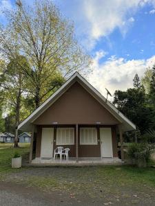 a small house with two white chairs in front of it at Harry World Parque Hotel in Curitibanos