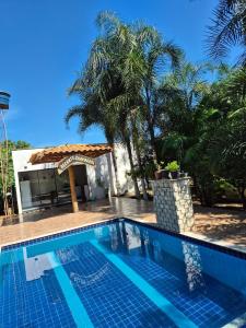 a pool in front of a house with palm trees at Recanto Chaparral in Aragoiânia