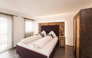 a bedroom with a large bed with white pillows at TANOVINUM Apartments in Villandro +66 photos