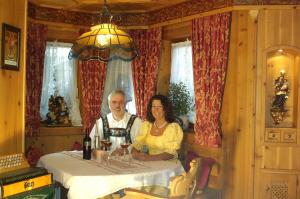 a man and woman sitting at a table with wine glasses at Ferienwohnung HERZOGSTAND in Krün