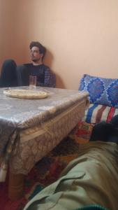 a man sitting at a table with a drink on it at اميزميز in Amizmiz
