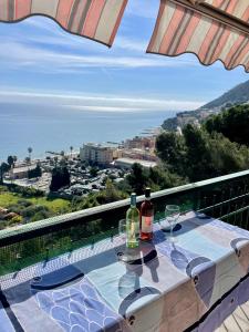 a table with two glasses and wine bottles on a balcony at Orizzonte guest house in Laigueglia