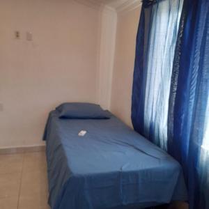 a small bedroom with a blue bed with a window at Dushi Boca Sami in Dorp Sint Michiel