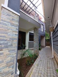 a house with a balcony and a brick walkway at Vine Suites Mbarara - 1 Bed Studio Apartment Near LDC & City Centre - Quiet & Convenient in Mbarara +3 photos