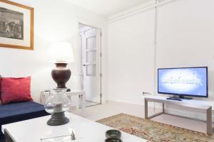 sala de estar con TV y mesa con lámpara. en For You Rentals Alfonso XIII Apartment, en Madrid