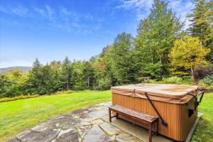 a hot tub on a stone patio with a bench at Mill Lane in Stowe