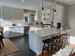 a kitchen with white cabinets and a island with bar stools at Mill Lane in Stowe