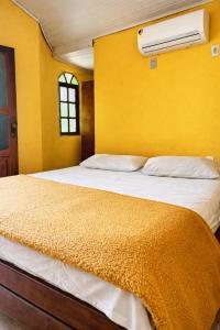 a bedroom with a bed with a yellow wall at Pousada Casarão Piúma in Piúma