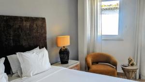 a bedroom with a bed and a chair and a window at Infante Guesthouse in Lagos