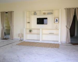 a living room with a tv on a white wall at MMG Resorts in Nāspur
