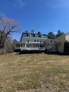 a large house sitting on top of a grass field at Ballard House Inn in Meredith