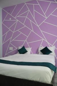 a bedroom with a purple wall and a bed with pillows at MMG Resorts in Nāspur +30 photos