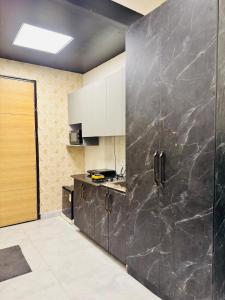 a kitchen with white cabinets and a black wall at The Skyline Studios in Ghaziabad