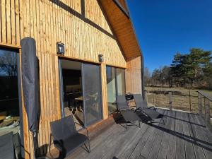 a wooden deck with two chairs and a building at Ohuta-Barn Vendégház in Parád