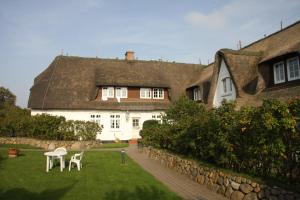 a large white house with a thatched roof at Apartmenthaus Witthüs in Wenningstedt