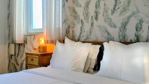 a bedroom with a bed with white sheets and pillows at Infante Guesthouse in Lagos