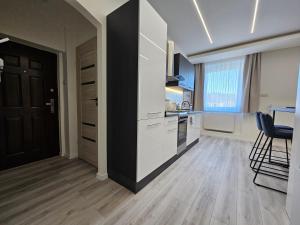 a kitchen with white cabinets and a black door at Barcika Prémium Stúdió in Kazincbarcika +15 photos