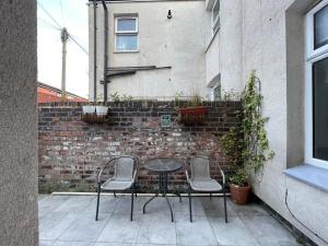 a patio with two chairs and a table in front of a brick wall at Rose Cozy House in Stockton-on-Tees