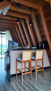 two chairs and a bar in a kitchen with wooden ceilings at Chalé Pôr do Sol Contenda in Contenda