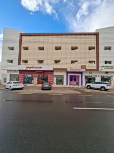a large building with cars parked in front of it at شقــق فندقيـة in Hail