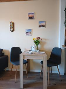 a wooden table with chairs and a vase of flowers on it at Sielpferdchen Bensersiel in Bensersiel