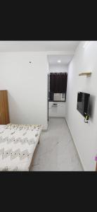 a white room with a bed and a television at Hotel Aura Avenue in Bathinda