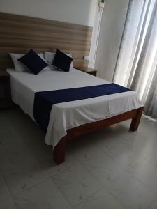 a large bed with blue and white sheets and pillows at Kimbar Suites in Mombasa